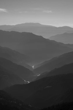 Sikkim Hindistan 'da sabahın erken saatlerinde içinden nehir akan tek renkli dağ silueti.