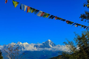 Arkasında karla kaplı dağlar olan renkli Tibet dua bayrağı Sikkim Hindistan 'daki manzarayla çok güzel görünüyor.