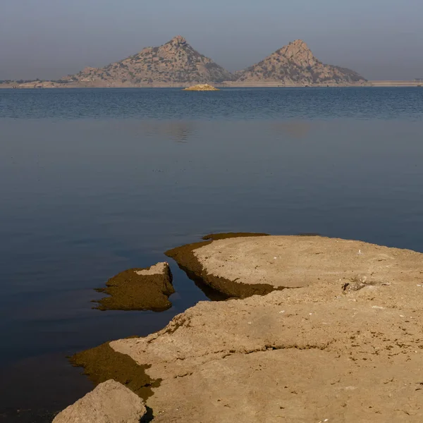 Jawai barajının berrak mavi gökyüzü ve Aravalli dağlarının seçici odak noktası Hindistan 'ın Rajasthan kentindeki Jawai' de sudaki yansıması.
