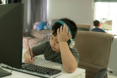Asyalı okul çocuğu çevrimiçi öğrenim kursunda sıkıntı ve zorluk gösteriyor, Covid-19 salgını sırasında sıkıcı evde eğitim veriyor, ev ödevlerini bitirmek için depresif hissediyor..