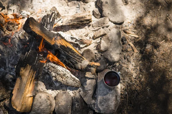 Metal mug near the fire in the camp. Top view.