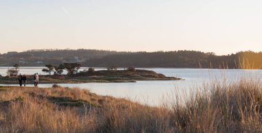 İki bilinmeyen çift Valdovinho Gölü 'nün yanında gün batımını izliyor.