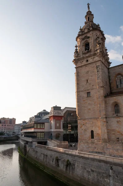 Bilbao, Euskal Herria, İspanya - 09 04 2018: San Anton kilisesi gün batımında Nervion nehri ve Ribera pazarının yanında. Tarihi XV yüzyıllık antik bina. Bir kaç küçük bulutlu açık mavi gökyüzü.