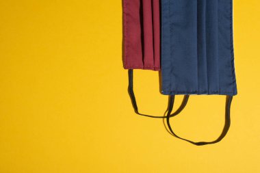 Hardal sarısı masa üzerinde kırmızı ve koyu mavi bir maske düğüm. Kopyalama alanı olan poster şablonu