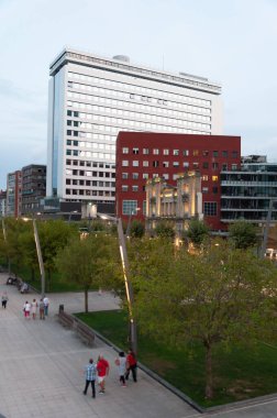 Bilbo, Euskal Herria, İspanya - 09 04 2018: İnsanlar yaz günbatımında Nervion nehir kenarındaki Atea kulelerinin yakınındaki Isozaki Büyükşehir Spor Salonu 'na yürüyorlar