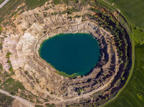 Aerial view of a crater created by mining machines and filled up with water creating an artificial lake.