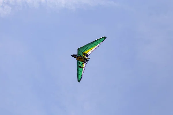 Motorized deltaplan flying in the air with beautiful blue sky on the background