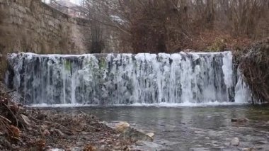 Bir kirli kahverengi nehirde yüzen buz parçaları.