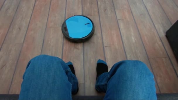 Person som kopplar av på en soffa med robot dammsugare smart applikations kontroll — Stockvideo