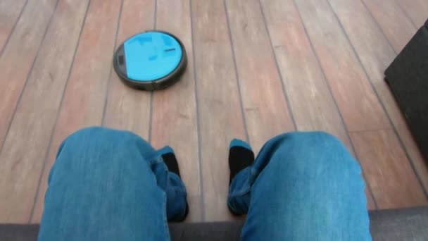 Člověk relaxovat na pohovce s dálkovým vakuum robot v ruce — Stock video