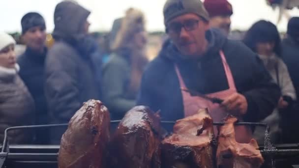 Cutting pieces of ham spit roasting on a barbecue — Stock Video