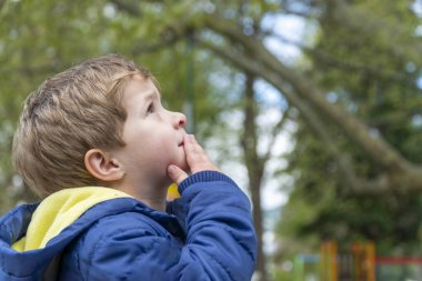 Küçük çocuk yukarı bakıyor ve bir şey için endişeleniyor.