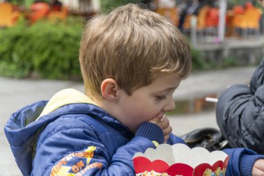 Parkta patlamış mısır yiyen küçük çocuk