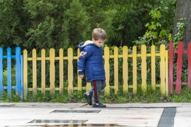Küçük çocuk yürüyor ve ayaklarına bakıyor.