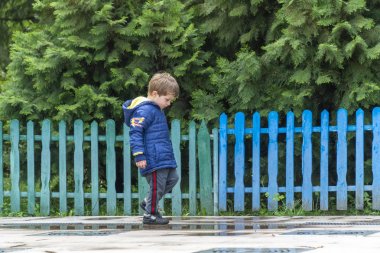 Küçük çocuk yürüyor ve ayaklarına bakıyor.