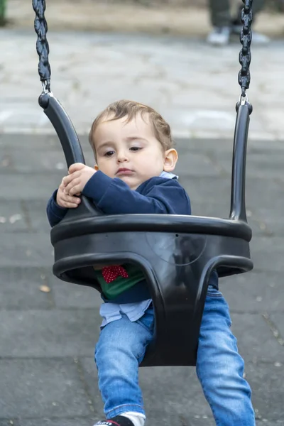 Child with uncertain face on a swing