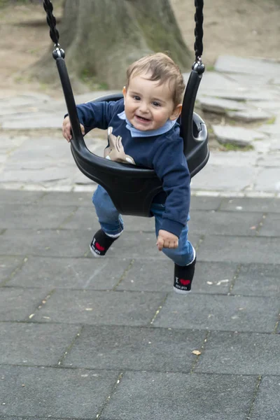 Lächelnder kleiner Junge auf einer Kinderschaukel — Stockfoto