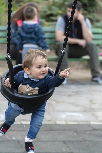 Kleiner Junge zeigt auf etwas auf einer Schaukel — Stockfoto