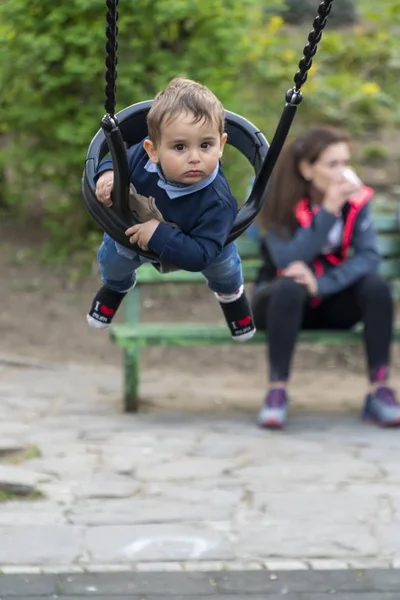 Lächelnder kleiner Junge auf einer Kinderschaukel — Stockfoto