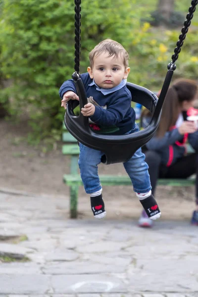 Lächelnder kleiner Junge auf einer Kinderschaukel — Stockfoto