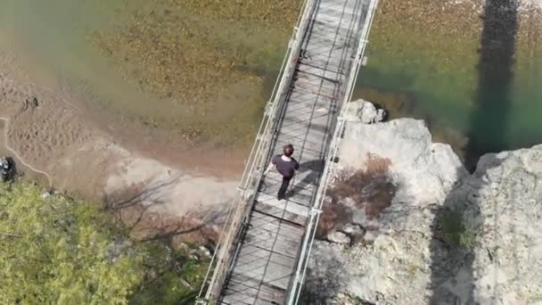 Vista aérea de uma pessoa que atravessa uma ponte suspensa — Vídeo de Stock