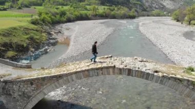 Taş köprüden geçen bir kişinin havadan görünümü