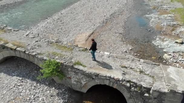 Luchtfoto van een persoon die een stenen brug oversteekt — Stockvideo