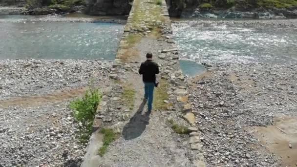 Luchtfoto van een persoon die een stenen brug oversteekt — Stockvideo