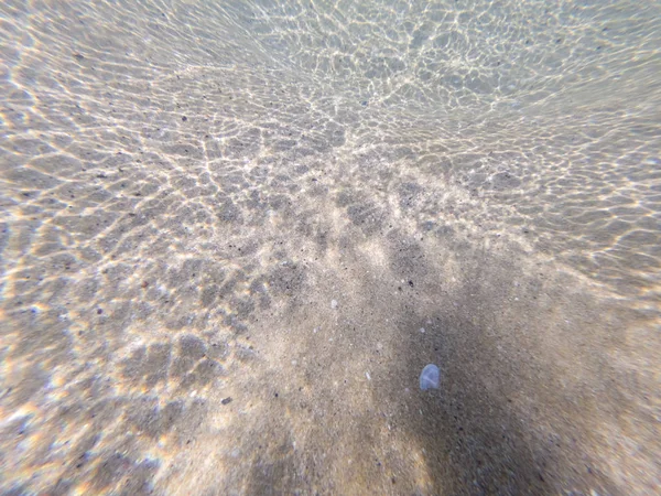 Piso de mar arenoso com reflexos de luz solar — Fotografia de Stock