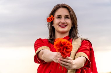 Geleneksel Hint kostümü giymiş genç bir kadın. Adı Sari. Kırmızı gelincik tarlasında yürüyor.