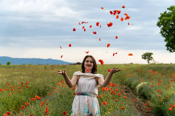 Ung Kvinna Vit Klänning Kastar Röda Vallmo Blommor Kameran — Stockfoto