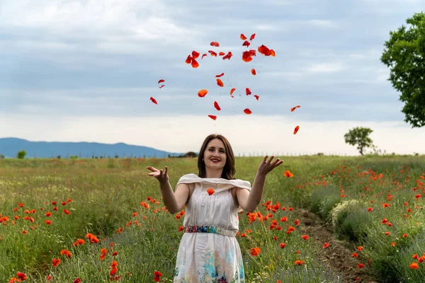 Ung Kvinna Vit Klänning Kastar Röda Vallmo Blommor Kameran — Stockfoto