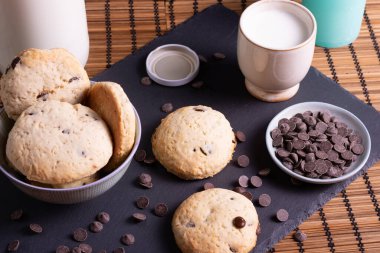 Tahtada çikolatalı kurabiye ve bambudan yapılmış bir bardak süt.