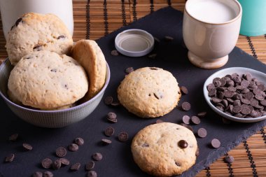 Tahtada çikolatalı kurabiye ve bambudan yapılmış bir bardak süt.