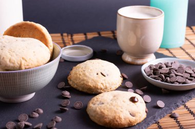 Tahtada çikolatalı kurabiye ve bambudan yapılmış bir bardak süt.