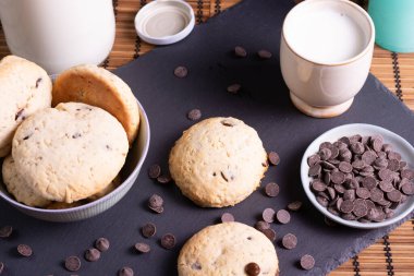 Tahtada çikolatalı kurabiye ve bambudan yapılmış bir bardak süt.