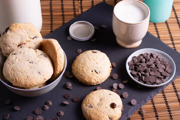 Tahtada çikolatalı kurabiye ve bambudan yapılmış bir bardak süt.