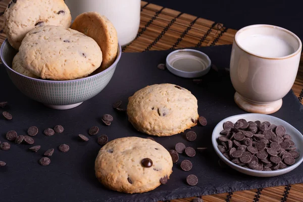 Tahtada çikolatalı kurabiye ve bambudan yapılmış bir bardak süt.