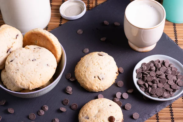 Tahtada çikolatalı kurabiye ve bambudan yapılmış bir bardak süt.