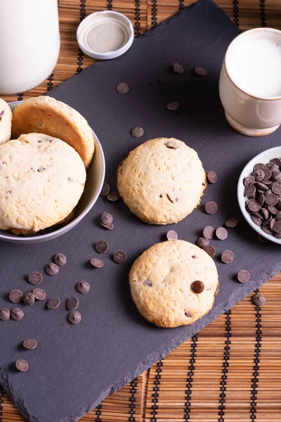 Tahtada çikolatalı kurabiye ve bambudan yapılmış bir bardak süt.