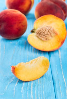 Dilimler ve yarı ahşap arka plan üzerinde dağınık olgun şeftali