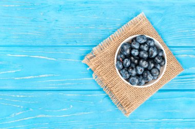 Yaban mersini çul ve boş ahşap arka plan, üstten görünüm kase dolu