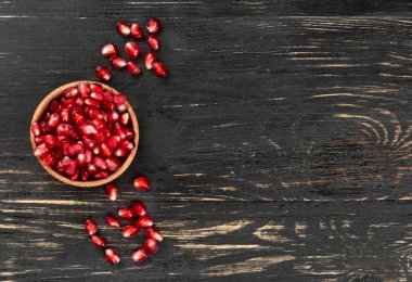 Boş bir ahşap zemin üzerine nar taneleri küçük kase