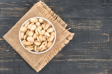 Çuval bezi ve boş bir ahşap arka plan üzerinde bir kase fıstık fındık