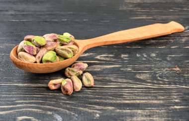 Bir kaşık ile karanlık bir tablo üzerinde dağınık fındık kabuğunda olmadan Antep fıstığı