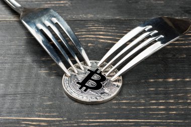 Gümüş bitcoin madeni para ile ahşap arka plan üzerinde iki çatal