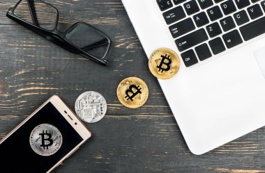 Bitcoin paralar ile bir dizüstü bilgisayar, bir yatak ve masada, üstten görünüm gözlük