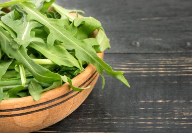 Karanlık bir tablo üzerinde bir kabın içinde yeşil roka yaprakları