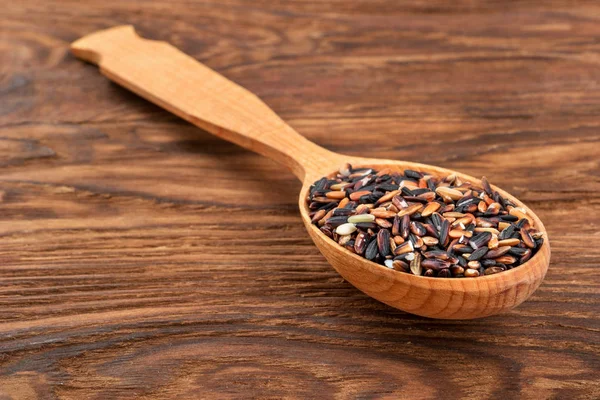 Raw wild rice in a spoon on the table close-up