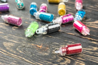 Makyaj ve tırnak tasarım ahşap arka plan üzerinde renkli sparkles dağınık şişe